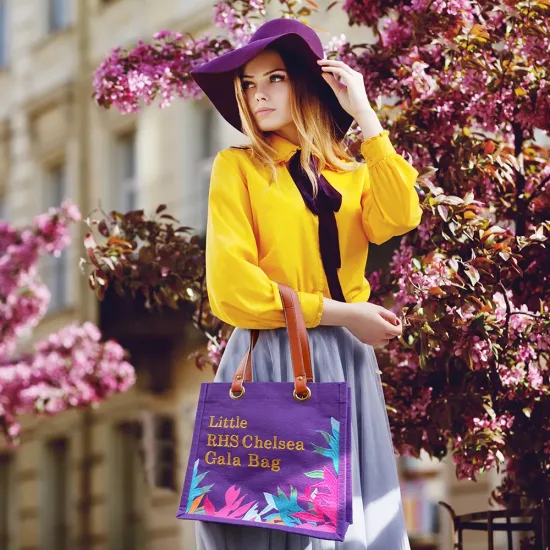 Outdoor portrait of young beautiful girl posing in street. Model wearing stylish hat, shirt, skirt, holding purple bag, handbag. City lifestyle. Female fashion concept. Copy, empty space for text